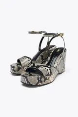 Sandalias de cuña con plataforma y estampado de serpiente en tonos grises y negros. Tira delantera ancha y tira trasera con hebilla metálica. Tacón de 10 cm y punta cuadrada.