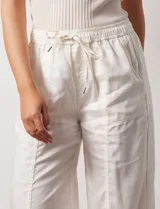 Pantalón palazzo color crudo, marca Nanette, con pretina elastizada, lazo de ajuste y bolsillos delanteros.