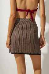 Minifalda marrón con rayas verticales negras y blancas, de corte cruzado con lazo lateral.