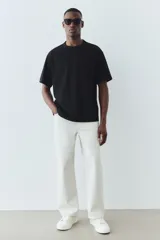 Remera negra de punto pesado con cuello redondo ribeteado, hombros caídos y bajo recto. Corte holgado confeccionada con tejido funcional COOLMAX®, una fibra de poliéster de secado rápido que elimina la humedad y regula la temperatura corporal.