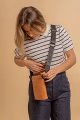 Bandolera tipo phone bag pequeña, color marrón claro, con correa de galón regulable. Tiene un compartimento principal y un bolsillo adicional con tapa.