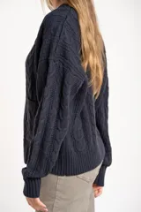 Cardigan de punto trenzado color azul marino, con escote en V, botones dorados y bolsillos delanteros.