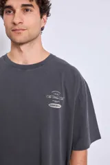 Remera gris oscuro de corte holgado con estampado pequeño en el pecho.