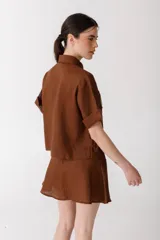 Camisa corta de manga corta color rojo, con doble cartera diagonal con botones de madera, cuello clásico y botamangas marcados. Tiene un bolsillo con aplique de crochet hecho a mano con forma de frutilla.