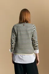 Cárdigan de tejido de punto a rayas horizontales anchas, color crema y negro. Presenta un cuello tipo chal que se anuda al frente como un lazo.