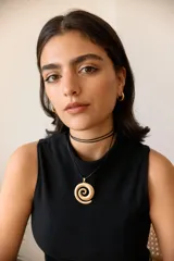 Collar con dije plateado en forma de espiral y cordón negro encerado.