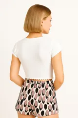 Remera blanca de algodón con elastano, de corte al cuerpo, manga corta y escote en V con volados en el ruedo y las mangas.