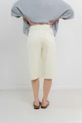 Bermuda color crema de tiro medio con corte recto y largo por la rodilla. Diseño amplio tipo culotte corto, con dobladillo ancho en el ruedo. Presenta bolsillos delanteros y traseros funcionales. Confeccionada en denim suave y cómodo.