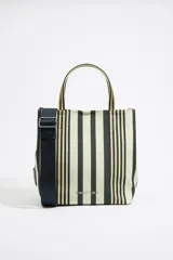 Bolso tipo tote de tela a rayas verticales en tonos crudo, negro y amarillo, con doble asa de mano y correa bandolera ajustable en color azul marino.