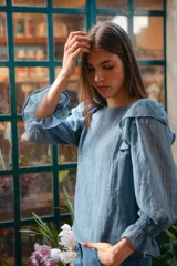 Blusa celeste de algodón con mangas largas abullonadas y puños elastizados con volados. Presenta volados en los hombros y escote redondo.