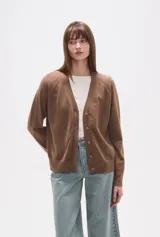 Cardigan de punto color blanco roto con motas oscuras, de manga larga y escote en V con cierre de botones frontales.