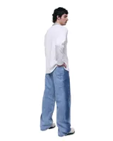 Pantalón unisex de denim 100% algodón con lavado degradado de celeste a azul. Tiro medio, calce wide y relajado, pierna extra ancha y caída larga. Cintura con elásticos laterales, costuras curvas y paneles que dibujan la pierna. Bolsillos delanteros y traseros curvos, presillas para cinto, cierre y botón metálico.