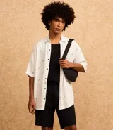Camisa blanca de viscosa con estampado de cocoteros, corte relaxed, cuello inglés, manga corta y cierre abotonado.