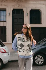 Chaleco de lana color crudo con diseño geométrico en negro y gris. Cuello redondo y cierre frontal con botones de cuero.