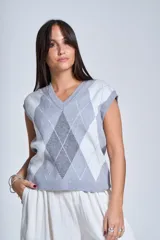 Chaleco tejido con patrón de rombos en tonos grises y blancos, con cuello en V y sisas amplias.