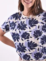 Remera blanca con estampado de flores y hojas en tonos pastel.