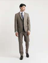 Traje de vestir color marrón topo, compuesto por saco de dos botones con solapa de muesca, dos bolsillos delanteros con solapa y un bolsillo superior. Pantalón de vestir con corte recto y bolsillos laterales. Incluye camisa blanca y corbata azul con lunares blancos.