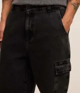 Bermuda masculina de jean color gris oscuro, corte holgado, con bolsillos cargo laterales, trabillas en la cintura y cierre con botón y cremallera.