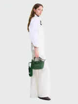 Bolso bandolera verde oscuro de cuero, con doble asa corta superior, correa larga extraíble y ajustable, cierre con solapa y botón a presión, y herrajes metálicos plateados.