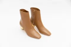 Bota de cuero color camel con punta cuadrada y cierre lateral. Tiene un taco bajo con forma de esfera dorada.