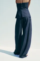 Pantalón de denim azul con pinzas delanteras, tiro medio, cintura con trabillas, bolsillos laterales y traseros.