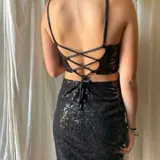 Vestido corto asimétrico con un hombro descubierto y dos breteles finitos que se atan cruzados en la espalda. El vestido es de lentejuelas plateadas y tiene un corte en la cintura.