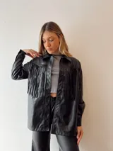 Sobrecamisa oversize de ecocuero negro con flecos en la espalda y tachas plateadas.