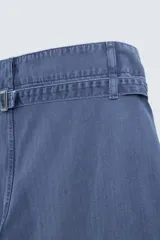 Pantalón azul de corte recto, con cintura ajustable, bolsillos laterales y traseros, y bolsillo tipo plastrón en la pierna. Tiene un lavado vintage con efecto de manchas.