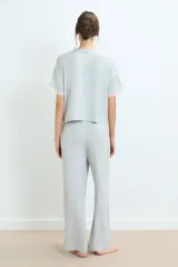 Conjunto de pijama negro, compuesto por una remera de manga corta con detalle de encaje en los puños y un pantalón largo de corte recto.