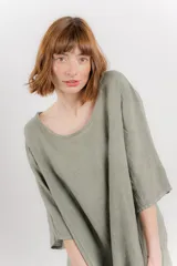 Vestido midi de lino con corte relajado y silueta fluida. Presenta escote redondo, mangas 3/4 y bolsillos laterales. Diseño minimalista y atemporal ideal para el verano.