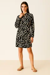 Vestido corto tipo camisa de manga larga con estampado abstracto en negro y beige, cuello camisero y cierre frontal con botones.
