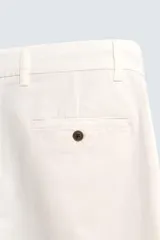 Pantalón chino negro de corte relajado (relaxed fit) con tiro medio, confeccionado en algodón con elasticidad. Presenta bolsillos delanteros y bolsillos traseros de vivo, con cierre frontal de cremallera y botón.