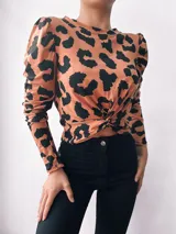 Remera color camel con estampado animal print negro, de mangas largas abullonadas y nudo en la parte delantera.