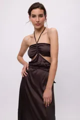 Vestido largo marrón de satén con escote halter, trenzas ajustables en cuello y cintura, lazos en el busto y aberturas en la cintura.