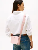 Bandolera Tommy Hilfiger color rosa con correa ajustable y logo dorado en el frente.