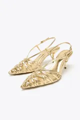 Zapato destalonado dorado con tiras finas entrecruzadas en la parte delantera, cierre con hebilla ajustable en la tira trasera, tacón fino alto y acabado en punta. Altura del tacón: 6 cm.
