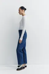 Pantalón de jean celeste de tiro alto, corte recto, con cinco bolsillos y cierre frontal con cremallera y botón metálico.