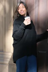 Polerón negro de corte oversize, con cuello drapeado y mangas largas caídas.