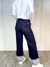 Pantalón de jean azul oscuro, de corte ancho, con bolsillos delanteros y traseros, y dobladillo ancho en el ruedo.