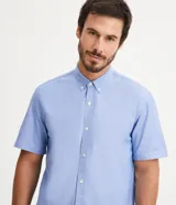 Camisa celeste de manga corta, corte comfort, con cuello abotonado y cierre frontal con botones.