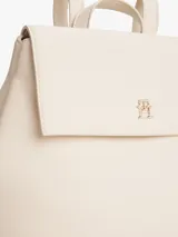 Mochila Tommy Hilfiger color crema con cierre de solapa magnético, asa superior y dos correas ajustables. Tiene un compartimento principal y un bolsillo interior con cremallera.
