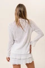 Blusa blanca de manga larga con cuello camisero y lazo en la cintura.