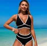 Conjunto de bikini negro con ribetes blancos, compuesto por un corpiño triangular con breteles finos y una bombacha de tiro alto.