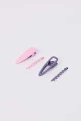 Set de cuatro hebillas para el pelo, dos tipo clip de color rosa y lila, y dos tipo pinza con forma ondulada en los mismos colores.