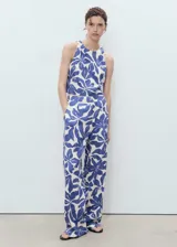 Top crop sin mangas con cuello redondo y diseño recto. Presenta un estampado floral en tonos azules sobre fondo crema, tirantes anchos y cierre de botones en la parte posterior. Confeccionado en una mezcla de viscosa y lino con forro de algodón.