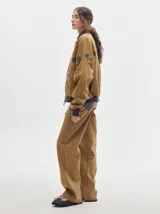 Pantalón de denim color marrón claro, de tiro alto, corte amplio y pinzas en la cintura.