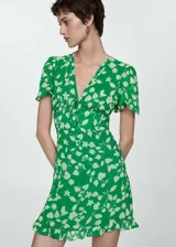 Vestido corto verde con estampado de flores blancas, escote en V con lazo, mangas cortas y falda con volantes.
