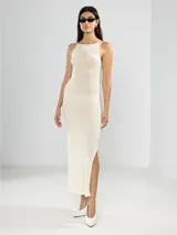 Vestido largo tejido color crudo, con cuello halter, espalda baja y abertura lateral.