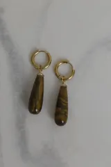 Par de aros colgantes con argolla dorada de acero quirúrgico hipoalergénico y dije en forma de gota de piedra natural blanca.