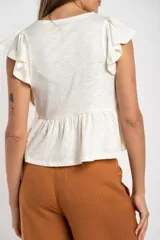 Remera color crudo de algodón con calados, corte al cuerpo y mangas cortas con volados.
